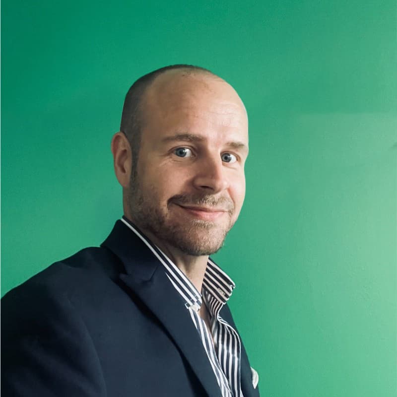 Jag vet inte vem personen på bilden är, men det är en man som ler och bär en mörk kavaj och en ...