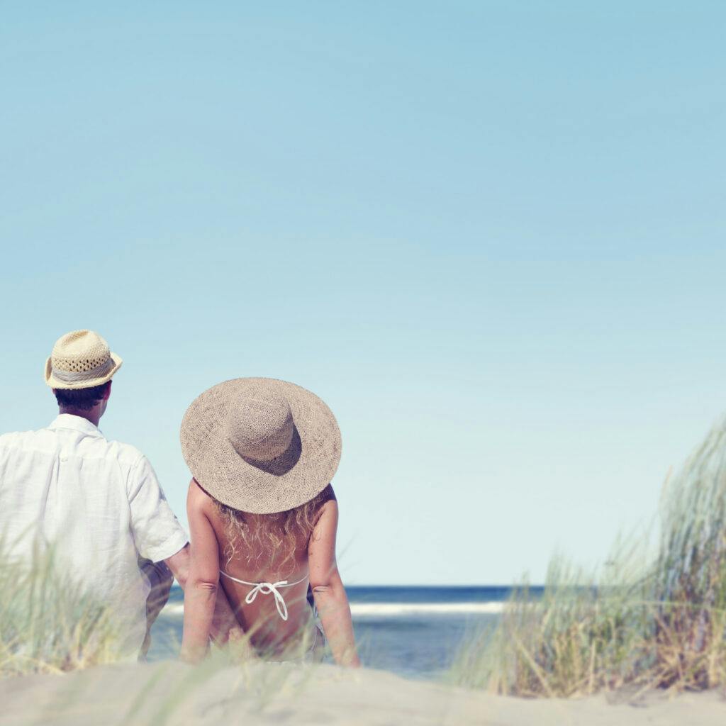 Kvinna och man sitter på en strand