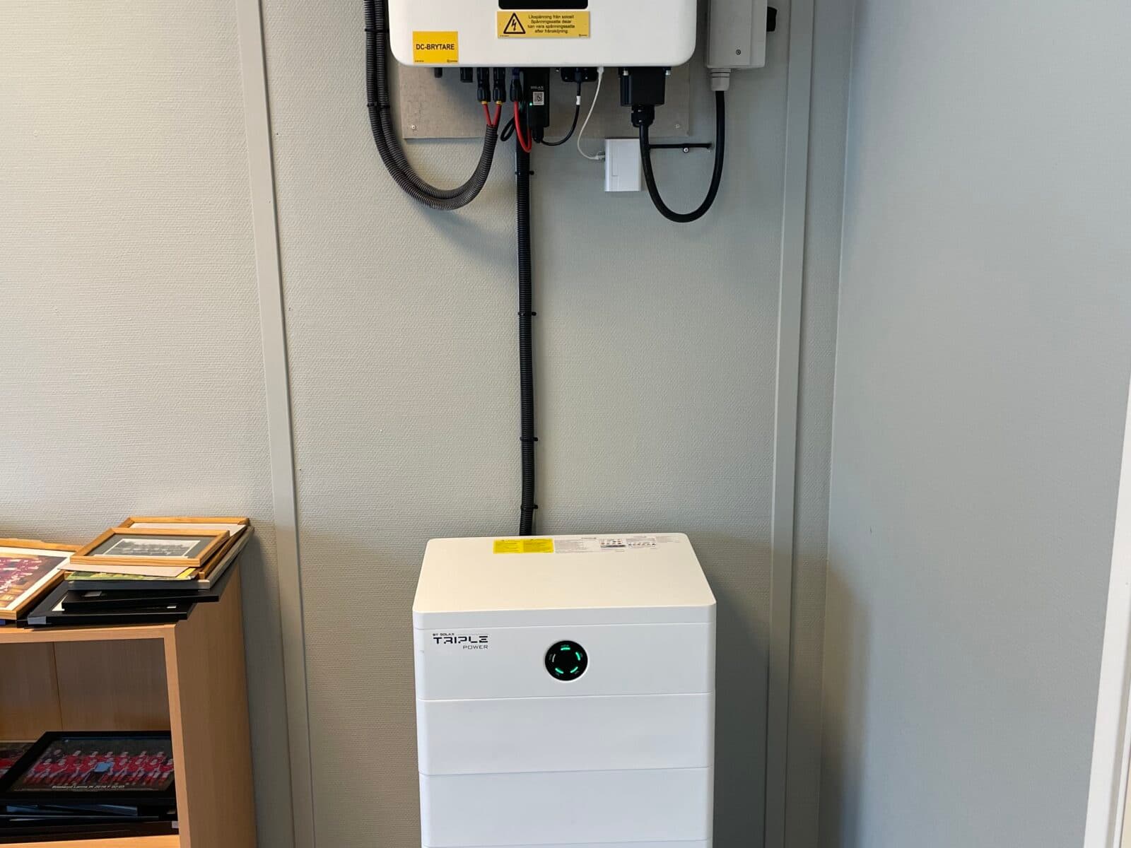 Väggmonterad solcellsinverter märkt "SolaX" och en batterienhet märkt "Vikus". ...